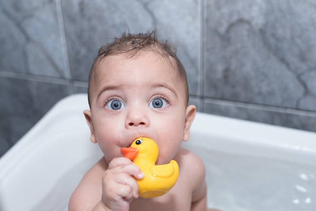 Niño de ojos azules bañándose en la bañera