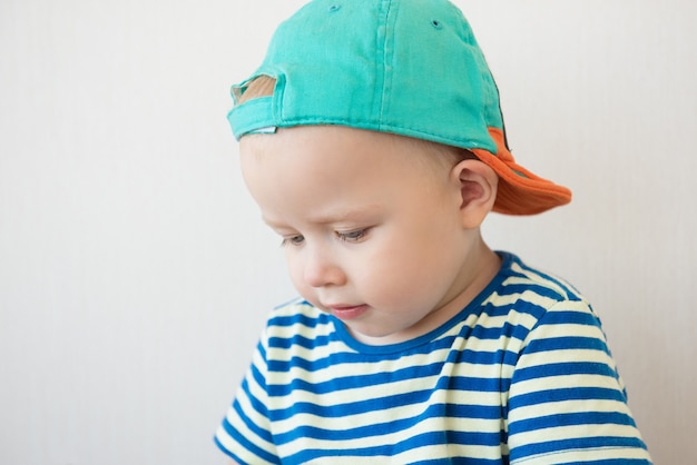 Niño con ojos azules en un retrato de camiseta y gorra a rayas