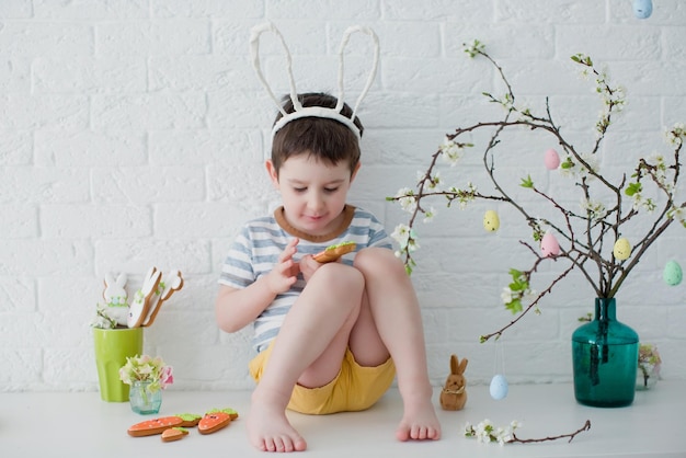 Niño con orejas de conejo come galletas