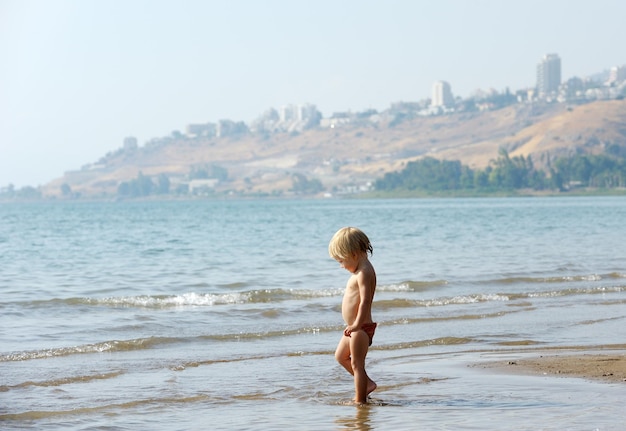 Niño en la orilla del lago Kinneret por la mañana