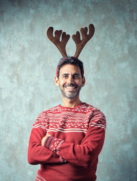 Niño oscuro con barba gris corta sonriendo en suéter rojo de navidad y diadema de asta de reno