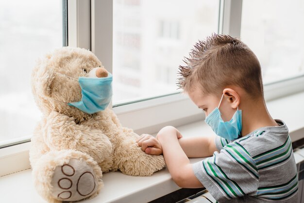 Niño con osito de peluche en cuarentena durante pandemia de coronavirus