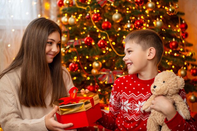 Niño con oso de peluche dando regalo de Navidad a su hermana concepto de celebración de Navidad