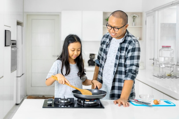 Niño y padre haciendo una tortilla para desayunar