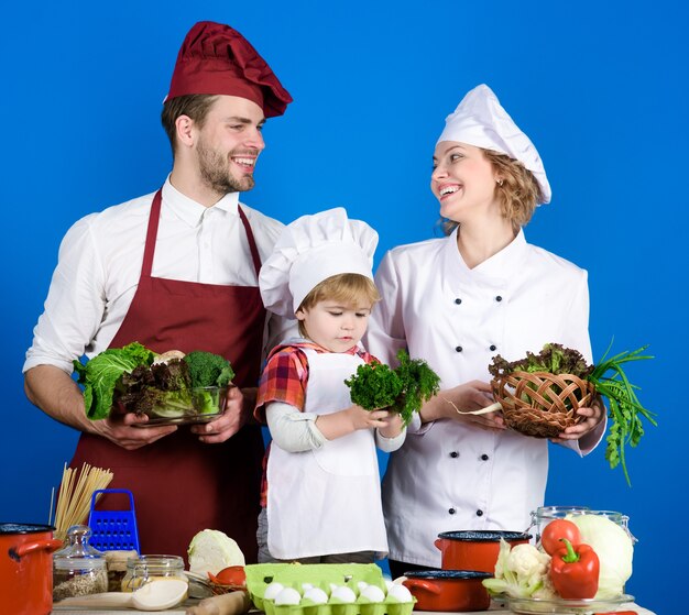 Niño con padres cocinando en la mesa de la cocina familia amorosa feliz preparando la cena juntos alegre