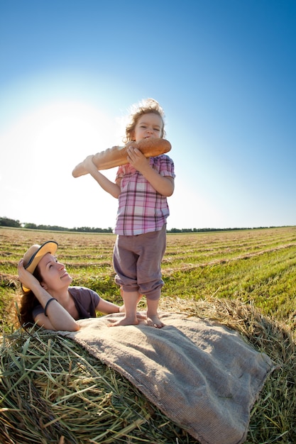 Niño con pan de pie en pajar en otoño campo de trigo Concepto de estilo de vida saludable