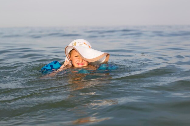 Un niño en Panamá está nadando en el agua Niño con un sombrero de ala ancha en el océano