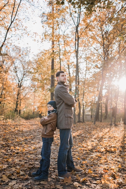 Niño con papá en el bosque de otoño con hojas de naranja