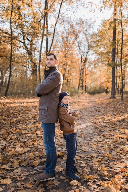 Niño con papá en el bosque de otoño con hojas de naranja