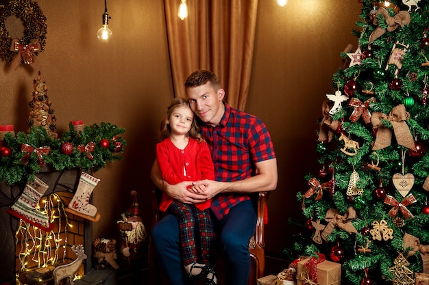 Niño con papá cerca del árbol de Navidad