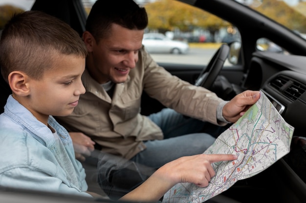 Foto niño y papá cerca de un coche eléctrico.