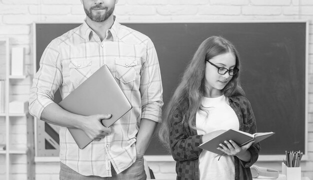 Niño y papá recortados en el aula con cuaderno y computadora en la paternidad de la pizarra