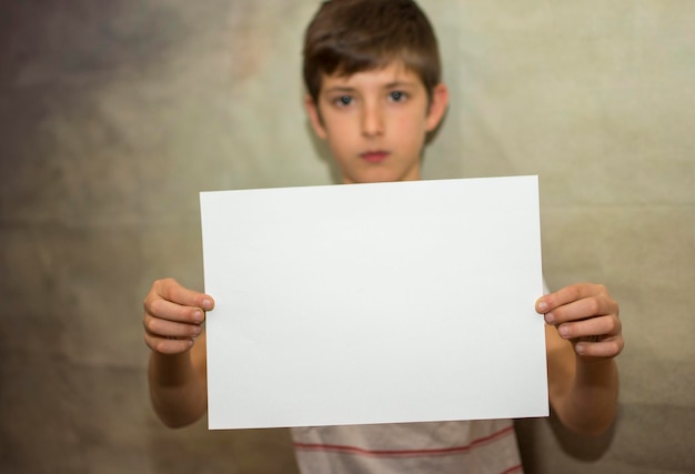 Un niño con un papel en blanco para la comunicación de mensajes, concepto de diseñadores de marketing