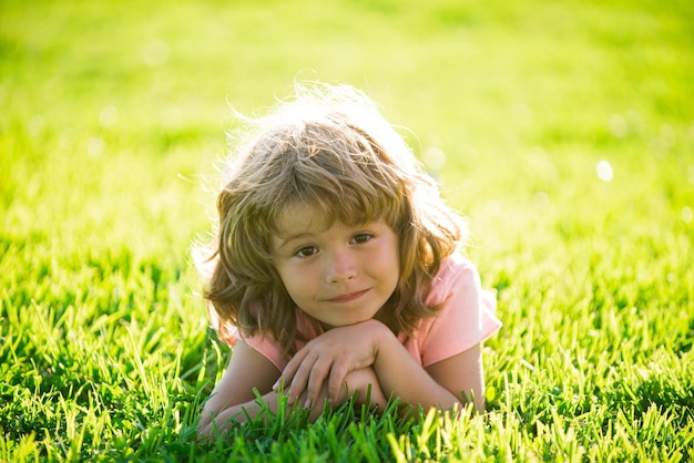 Niño en el parque al aire libre. Niño de primavera tirado en la hierba. Paseo de chicos de verano. Adaptación infantil.