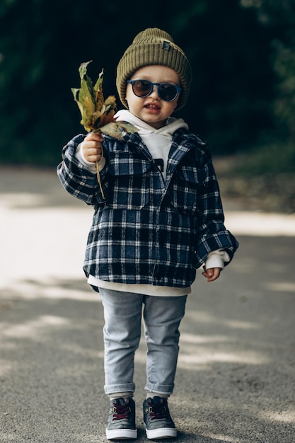 Niño en el parque con hojas de otoño