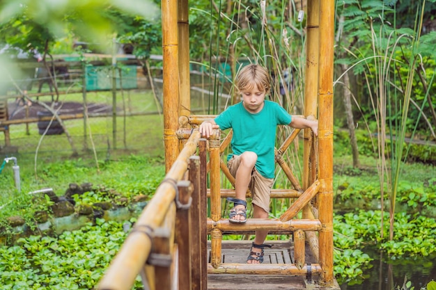 El niño en el parque infantil de bambú Parque infantil ecológico