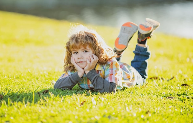 Niño en el parque Niño al aire libre Primavera Niño tirado en la hierba Paseo de verano Adaptación de los niños