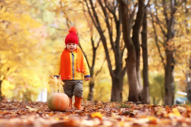 Niño en el parque de otoño con calabaza jugar y divertirse