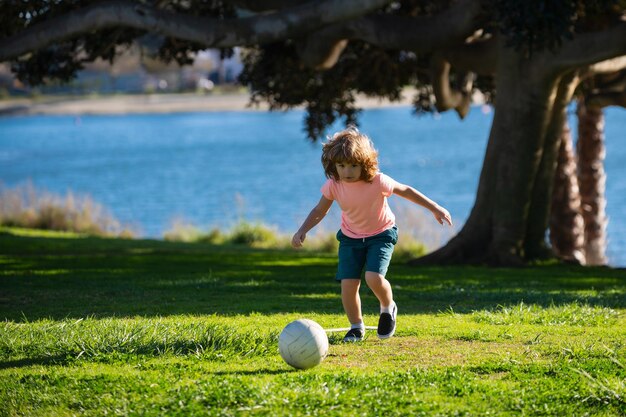 Niño pateando fútbol en el campo de deportes durante el partido de fútbol