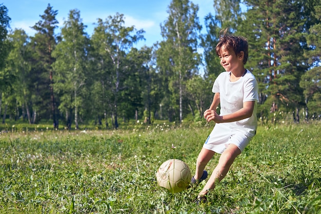 Niño pateando una pelota de fútbol en el campo