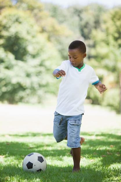 Niño pateando una pelota de fútbol en el parque