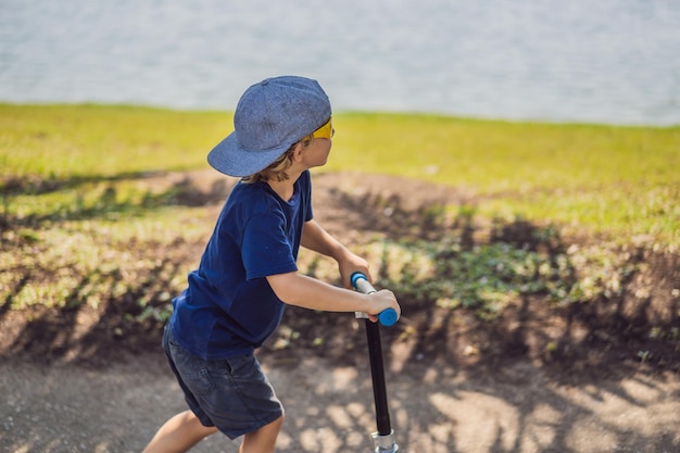 Niño en patinete en el parque los niños aprenden a patinar sobre ruedas niño patinando en verano soleado