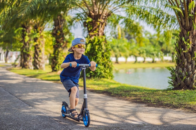 Niño en patinete en el parque Los niños aprenden a patinar sobre ruedas Niño pequeño patinando en un día soleado de verano Actividad al aire libre para niños en una calle residencial segura Deporte activo para niños en edad preescolar