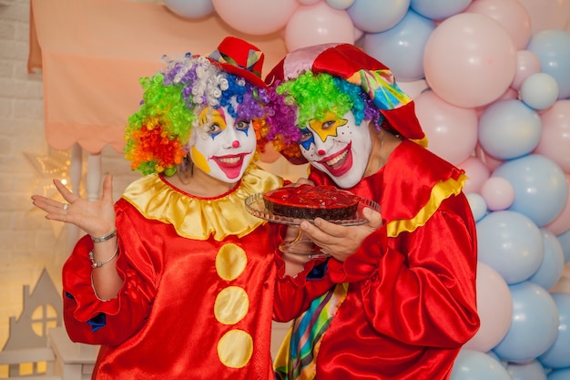 Niño payaso con niña payaso están peleando por un delicioso pastel