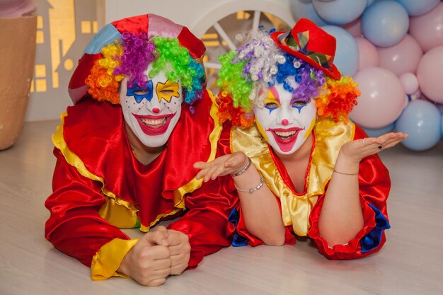 Foto niño payaso con niña payaso están peleando por un delicioso pastel