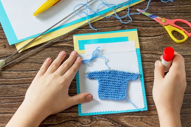 El niño pega detalles Tarjeta con chaleco de punto Tarjeta de felicitación con manualidades de recién nacido para niños