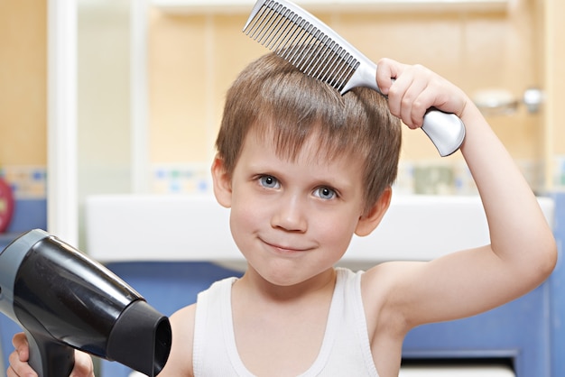 Foto niño con un peine y secador de pelo