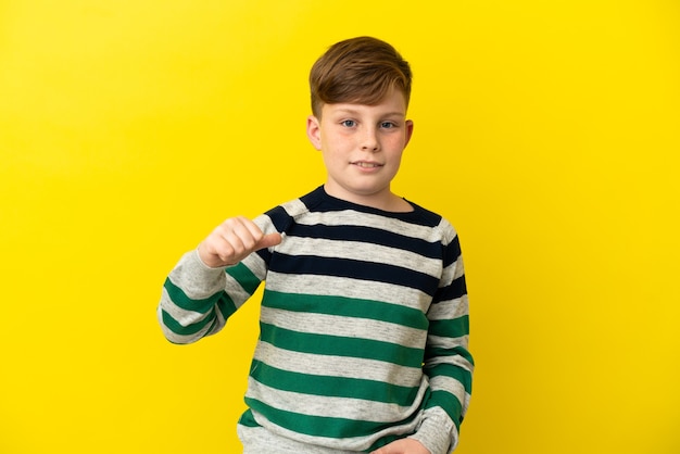 Niño pelirrojo aislado sobre fondo amarillo orgulloso y satisfecho de sí mismo