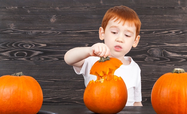 Niño pelirrojo esconde una calabaza con sorpresa y disgusto, mira lo que hay dentro