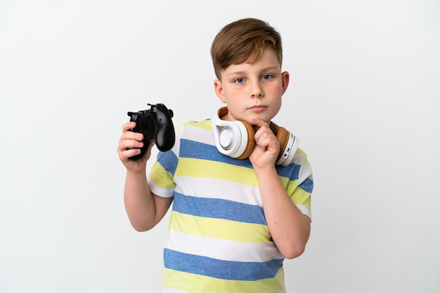 Niño pelirrojo sosteniendo un mando de juego aislado sobre fondo blanco mirando hacia arriba mientras sonríe