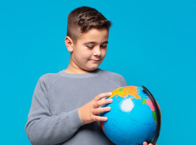 Foto niño pensando expresión y sosteniendo un modelo de mapa del mundo