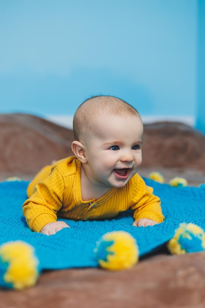 Un niño pequeño de 45 meses yace en una cama con ropa amarilla El niño comienza a sostener su cabeza Ropa de bebé