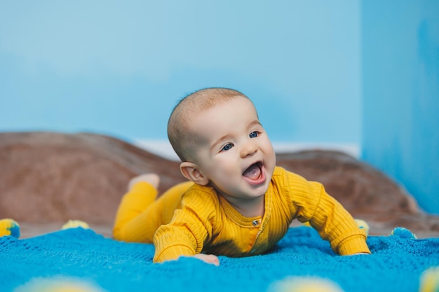 Un niño pequeño de 45 meses yace en una cama con ropa amarilla El niño comienza a sostener su cabeza Ropa de bebé