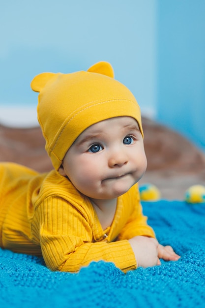 Un niño pequeño de 45 meses yace en una cama con ropa amarilla El niño comienza a sostener su cabeza Ropa de bebé