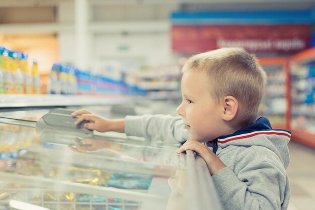 Un niño pequeño de 57 años abre una cámara frigorífica en un supermercado