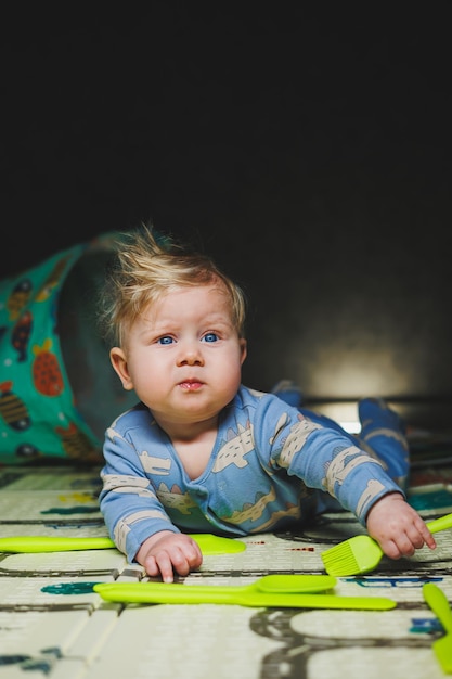 Un niño pequeño de 7 meses yace en el suelo y juega con juguetes de goma El bebé juega con juegos educativos