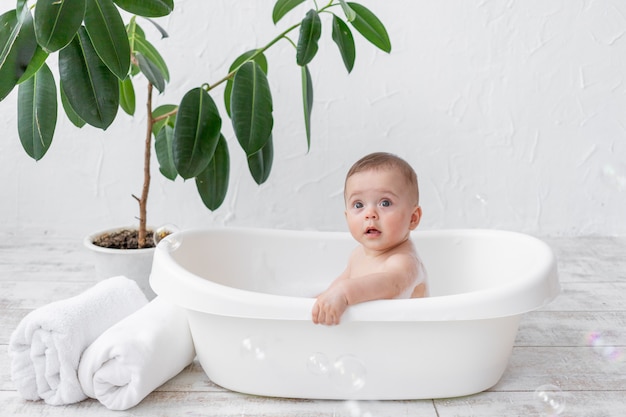 Un niño pequeño de 8 meses se baña con espuma y pompas de jabón.