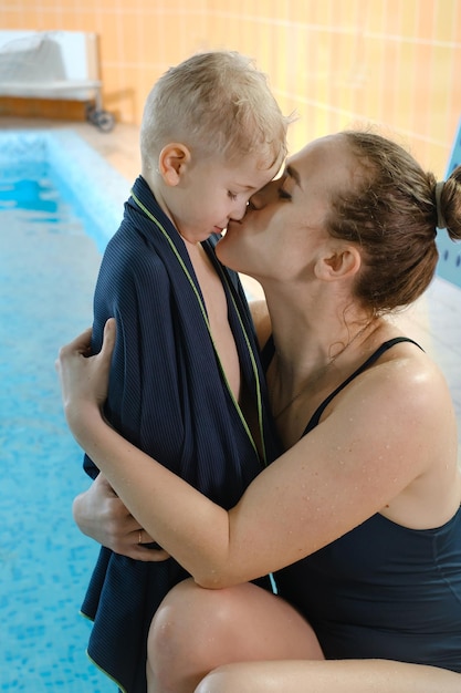 Niño pequeño abrazando a la madre después de nadar en la piscina cubierta