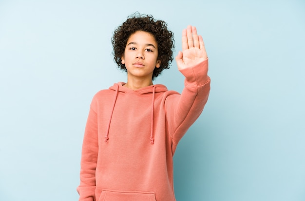 Niño pequeño afroamericano aislado de pie con la mano extendida que muestra la señal de stop, prevonting.