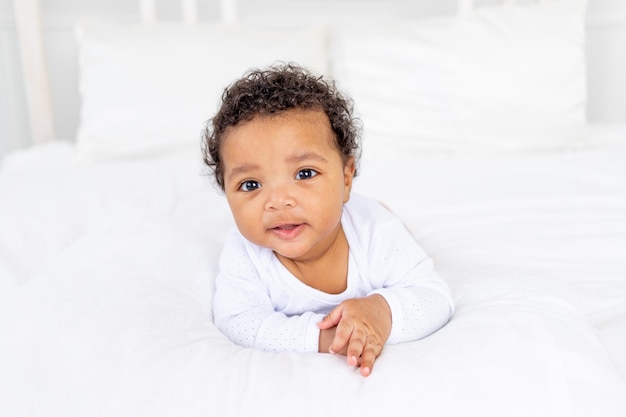 Foto niño pequeño afroamericano en una cama blanca en el dormitorio