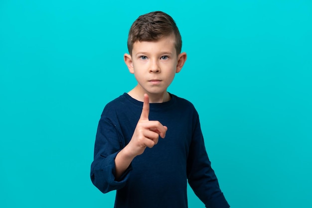 Niño pequeño aislado de fondo azul frustrado y apuntando al frente