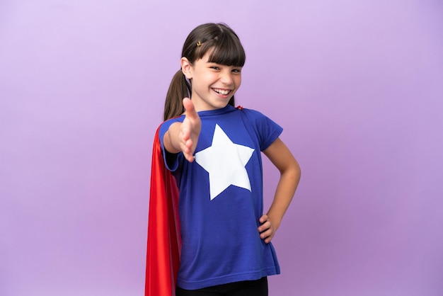 Niño pequeño aislado de fondo morado disfrazado de superhéroe y haciendo un trato