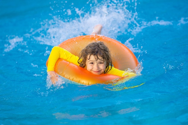 Niño pequeño con anillo de goma en la piscina diversión de verano niño pequeño nadando en la piscina niño en la piscina