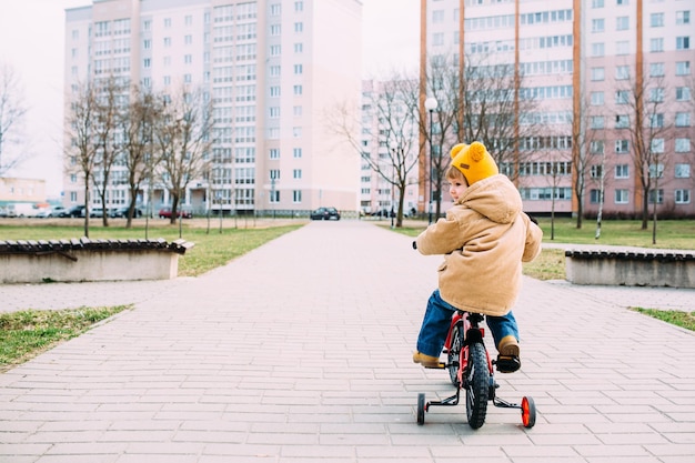 un niño pequeño aprende a andar en bicicleta por primera vez en la ciudad en primavera