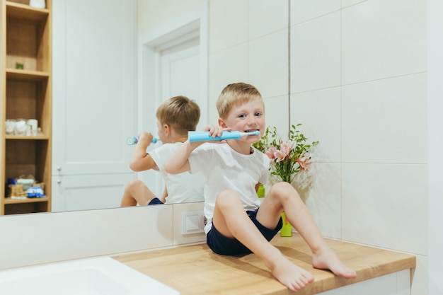 Niño pequeño aprende a cepillarse los dientes en el baño