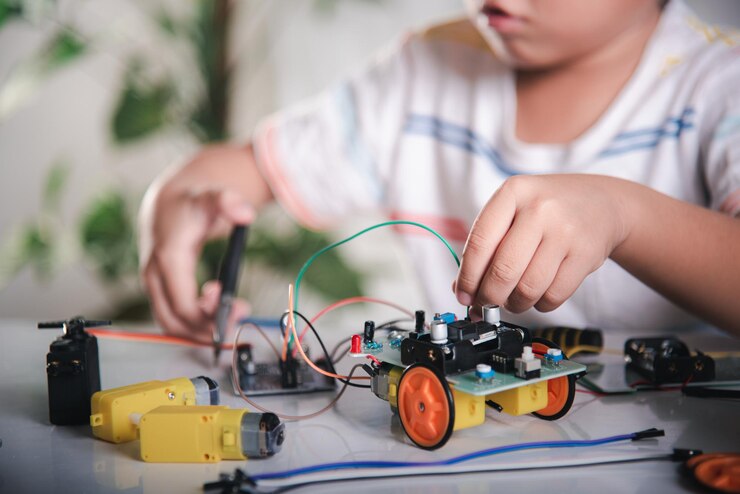 Foto niño pequeño aprende remotamente en línea con juguete de coche antes de enviar código niño asiático conectando energía y cable de señal al chip de sensor con arduino robot coche steam educación ai curso de tecnología de aprendizaje